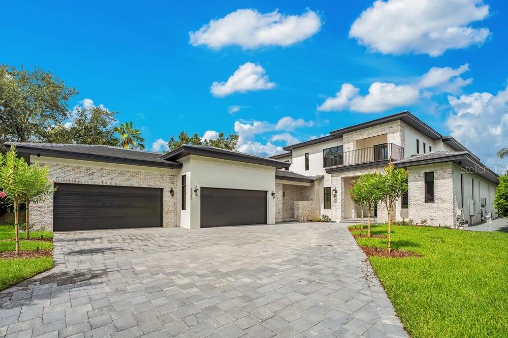 A modern two-story house with a stone facade, a three-car garage, and a paved driveway — 8342 BOYLA COURT, WINDERMERE, FL