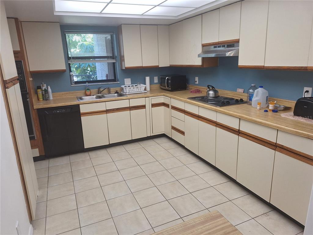 A kitchen with off-white cabinets, wood trim, laminate countertops, and light-colored floor tiles — 504 S FLORIDA AVENUE UNIT 215, TARPON SPRINGS, FL