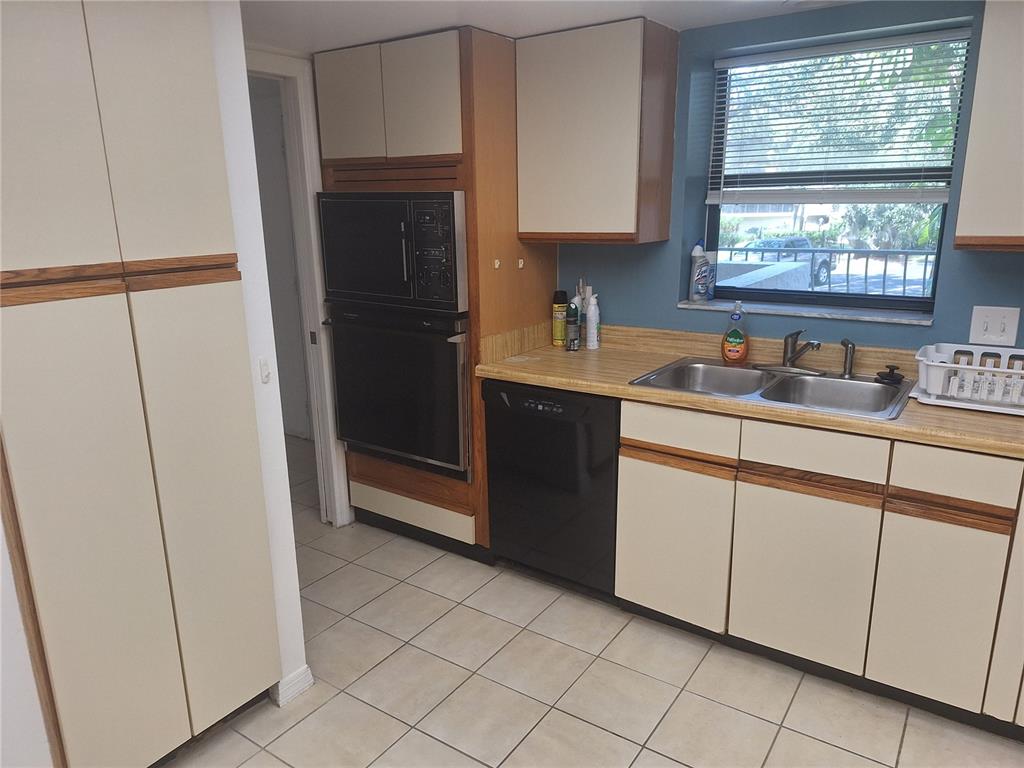 A kitchen features light-colored cabinets, a black dishwasher, a wall oven, and a double sink — 504 S FLORIDA AVENUE UNIT 215, TARPON SPRINGS, FL