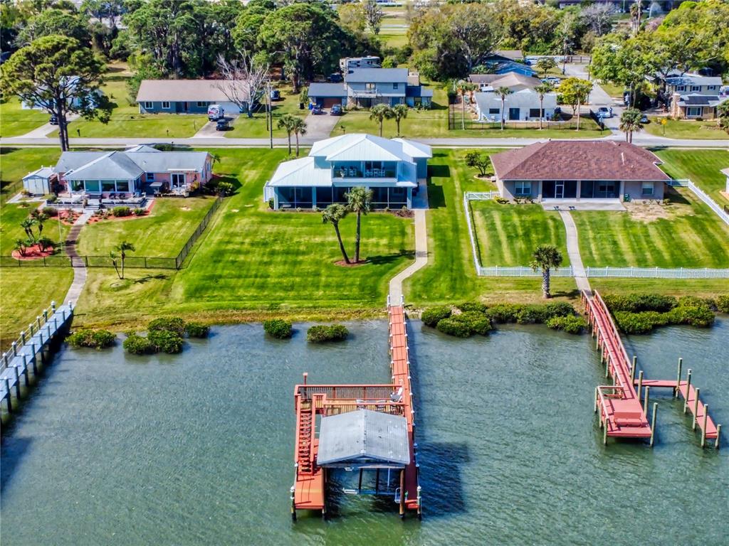 An aerial view shows three waterfront houses with private docks extending into the water — 2019 S RIVERSIDE, EDGEWATER, FL