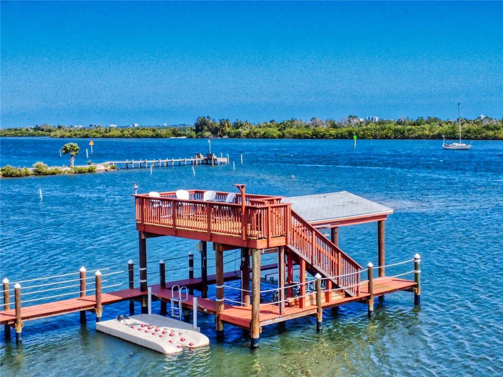 A wooden two-story boat dock with a covered deck sits over blue water — 2019 S RIVERSIDE, EDGEWATER, FL