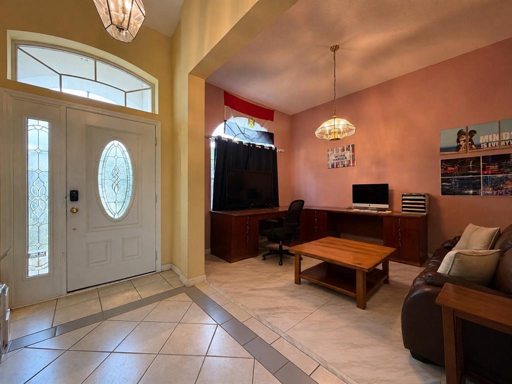 A home office with a desk, computer, coffee table, and sofa near the front entrance — 3637 DEVEREAUX COURT, ORLANDO, FL