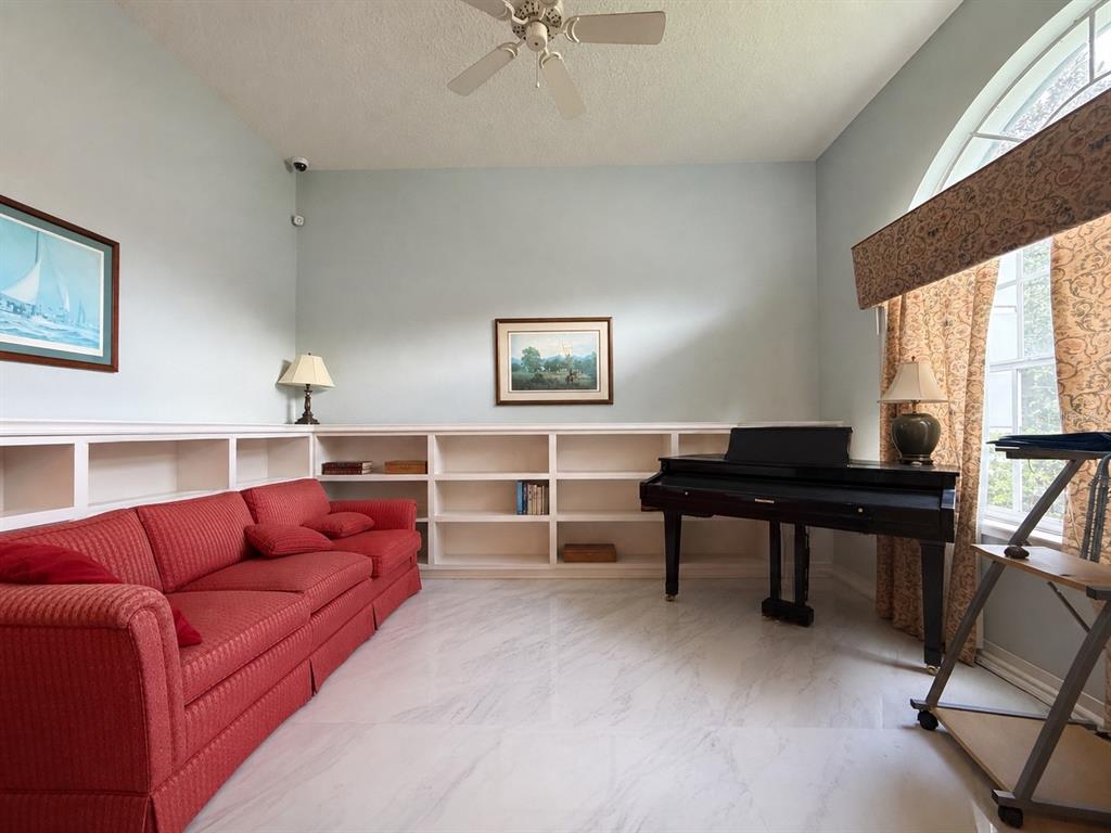 A room with a red sofa, built-in bookshelves, a piano, and light-colored tile flooring — 3637 DEVEREAUX COURT, ORLANDO, FL