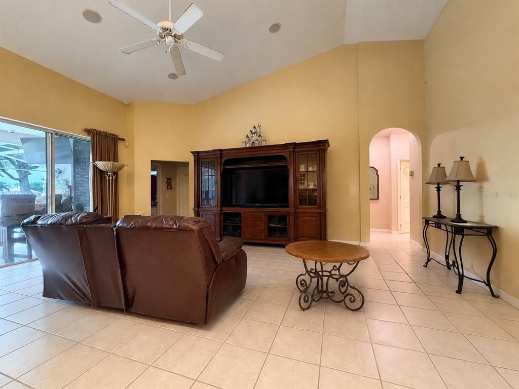 A living room features a large entertainment center, brown leather sofa, and tile flooring — 3637 DEVEREAUX COURT, ORLANDO, FL