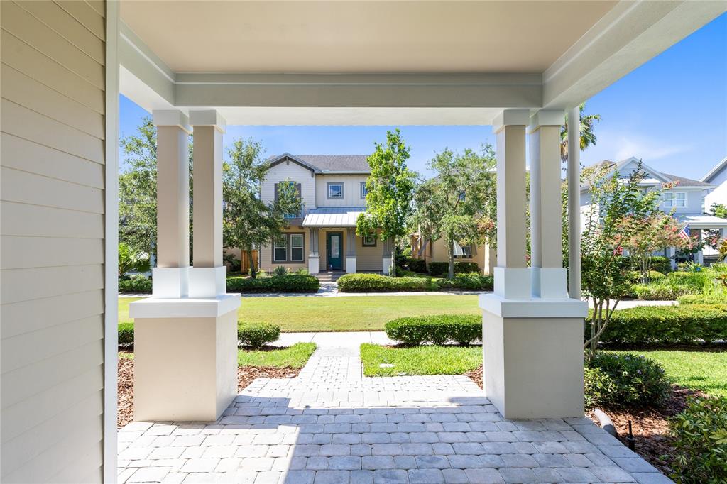 A view from a covered porch looking across a lawn toward a neighboring house — 8460 BERGSON PLACE, ORLANDO, FL