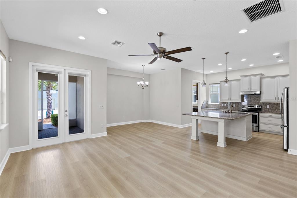 An open-concept kitchen and dining area features light wood flooring, white cabinetry, and an island — 8460 BERGSON PLACE, ORLANDO, FL