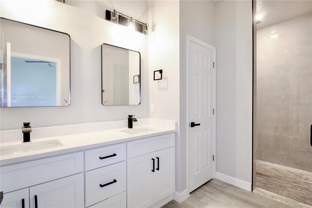 A modern bathroom features a white double vanity with black hardware and a walk-in shower — 4000 GARIENDA AVENUE, SEBRING, FL