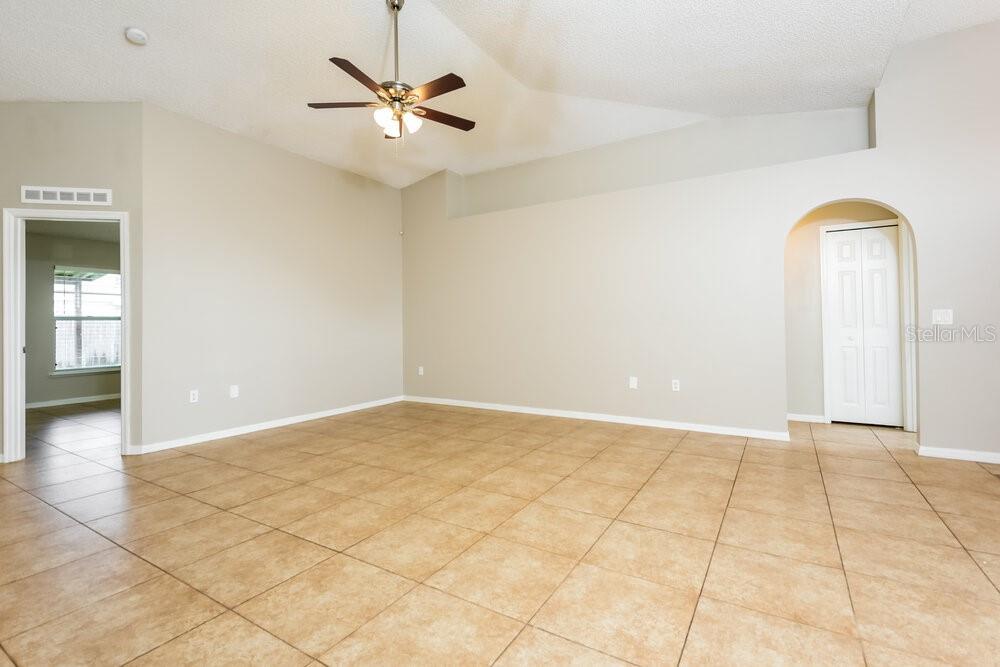 An empty room features beige walls, a vaulted ceiling with a fan, and tiled flooring — 346 VITORIA ROAD, DAVENPORT, FL