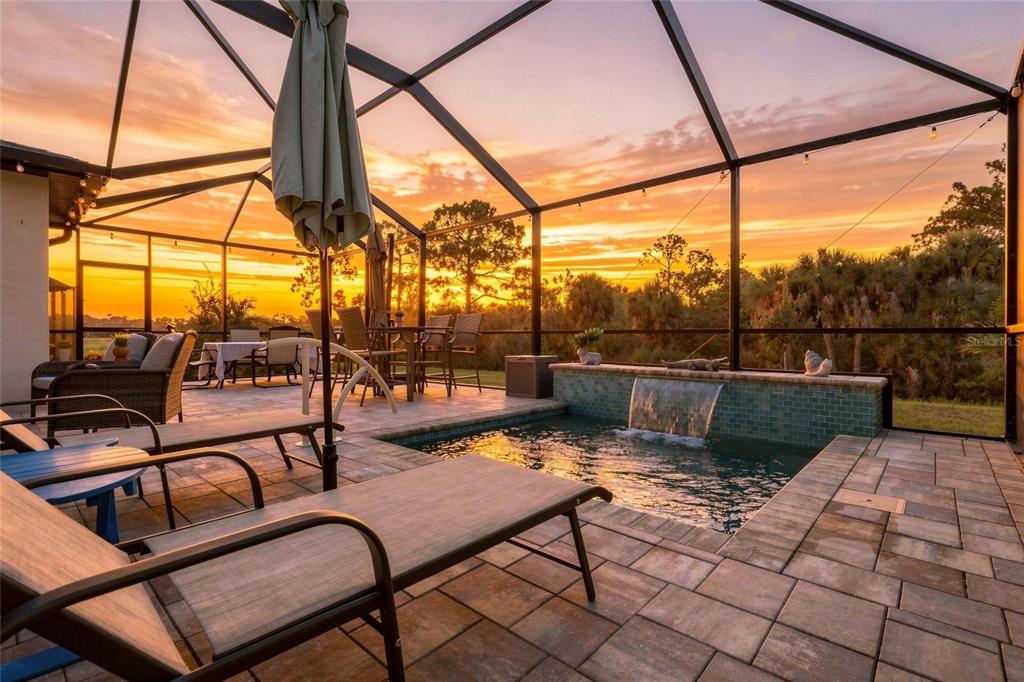 A screened-in patio features a small pool with a waterfall and outdoor dining furniture — 152 LAZY SHORE DRIVE, NOKOMIS, FL