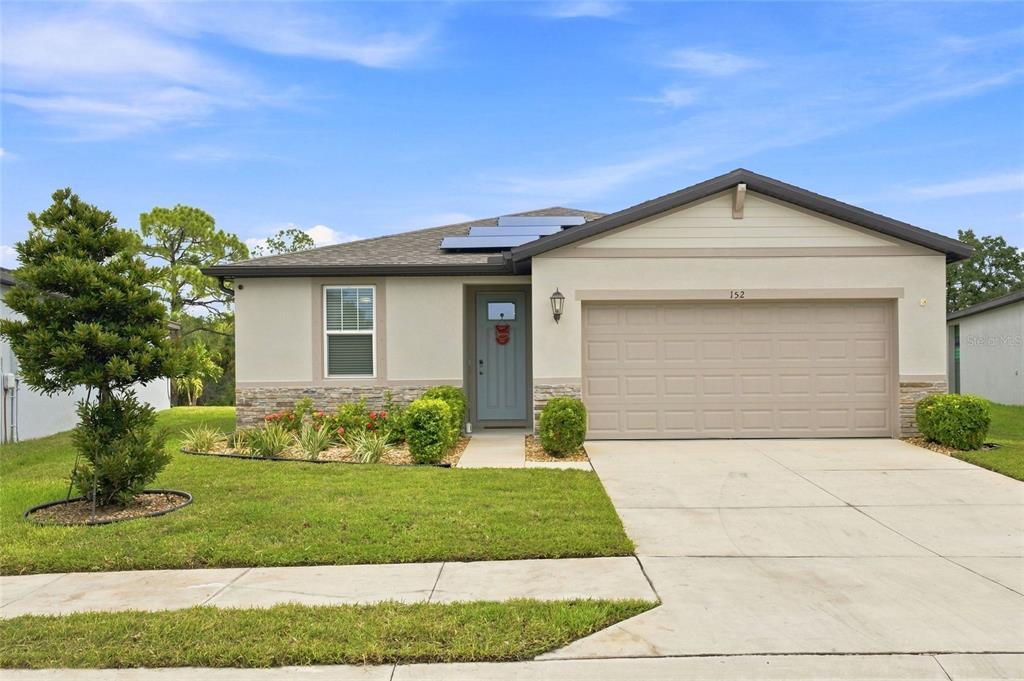 A single-story house with a light-colored facade, a two-car garage, and solar panels on the roof — 152 LAZY SHORE DRIVE, NOKOMIS, FL