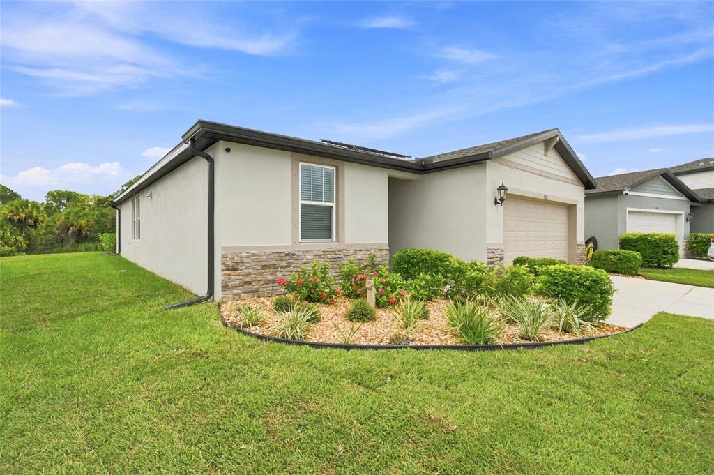 A single-story house with a beige stucco exterior, stone veneer accents, and a front garage — 152 LAZY SHORE DRIVE, NOKOMIS, FL