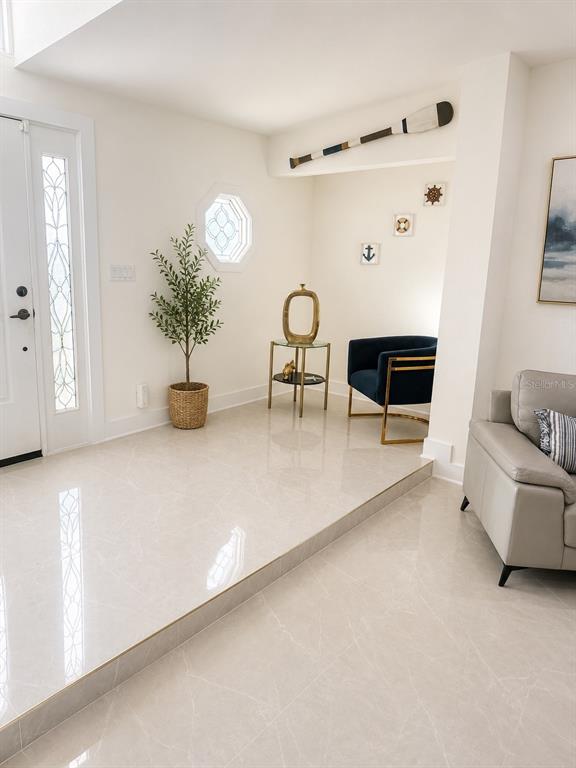 A covered patio features a paver floor, two wicker chairs, and a wooden bench — 452 BATH CLUB BOULEVARD N, NORTH REDINGTON BEACH, FL