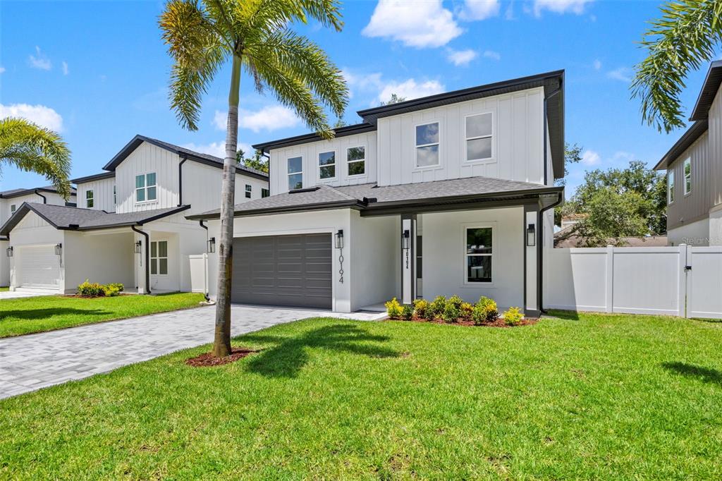 A two-story white house with a gray garage door and a paved driveway — 10194 HODSON PLACE, SEMINOLE, FL