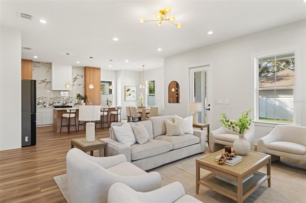 An open-concept living room and kitchen featuring light wood floors and modern neutral furniture — 10194 HODSON PLACE, SEMINOLE, FL