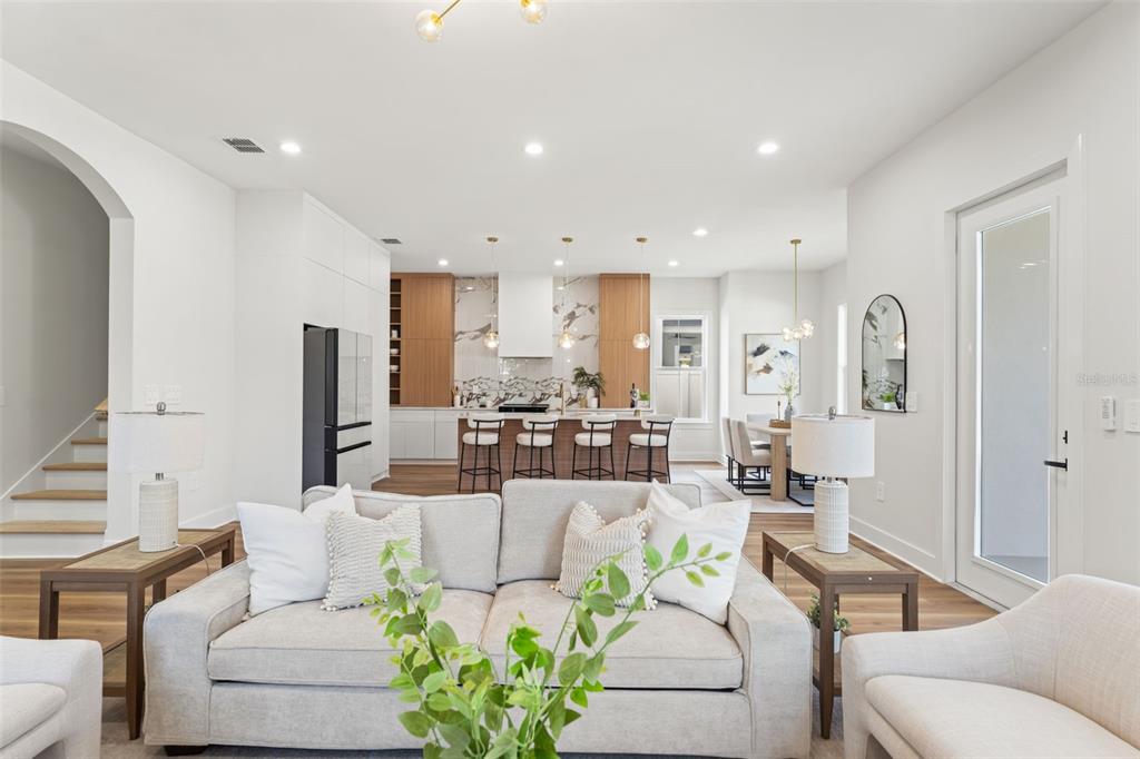 A modern open-concept living room features a sofa, kitchen island, and dining area — 10194 HODSON PLACE, SEMINOLE, FL
