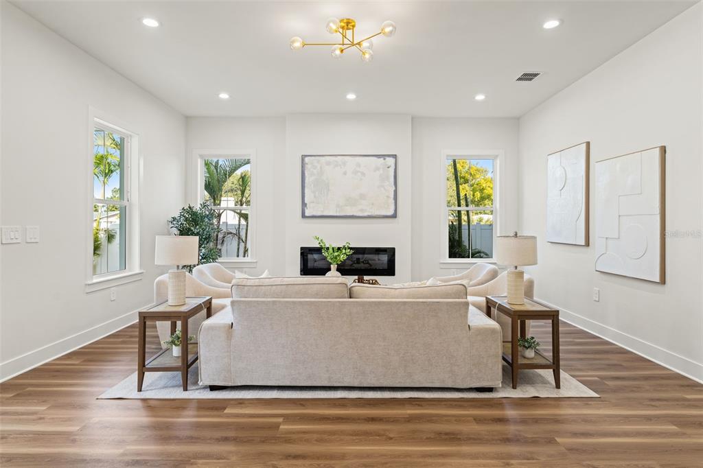 A living room features a beige sofa, two armchairs, a fireplace, and wood-look flooring — 10194 HODSON PLACE, SEMINOLE, FL