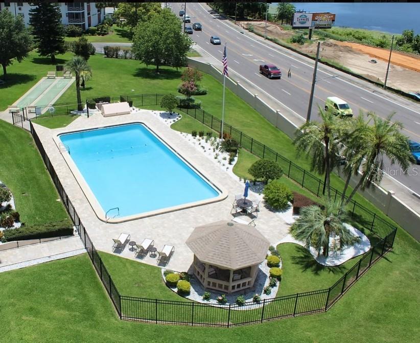 An aerial view of a swimming pool, gazebo, and shuffleboard court next to a road — 1776 6TH STREET NW UNIT 504, WINTER HAVEN, FL