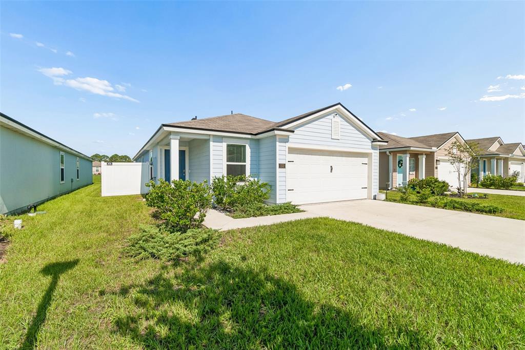 A light blue, single-story suburban house with a white garage and a grassy front yard — 153 ASHBROOK STREET, ST AUGUSTINE, FL