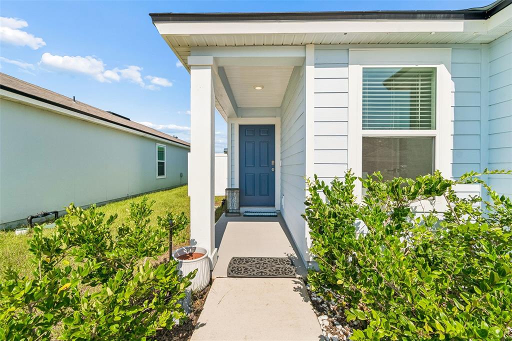A light blue house exterior features a covered entryway with a blue front door — 153 ASHBROOK STREET, ST AUGUSTINE, FL