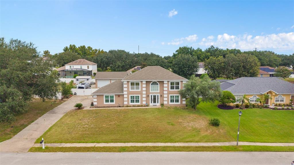 A two-story suburban house with a tan exterior, white trim, and a large front lawn — 16017 LANESBORO COURT, CLERMONT, FL