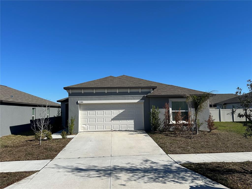 A single-story gray house with a two-car garage and a concrete driveway — 5380 BLUE HORIZON WAY, WIMAUMA, FL