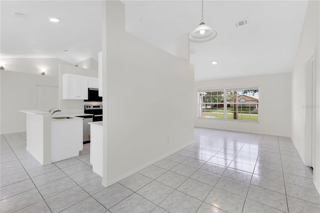 A kitchen with white cabinets and a breakfast bar overlooks a tiled dining area — 1097 DEPOT COURT, WINTER GARDEN, FL