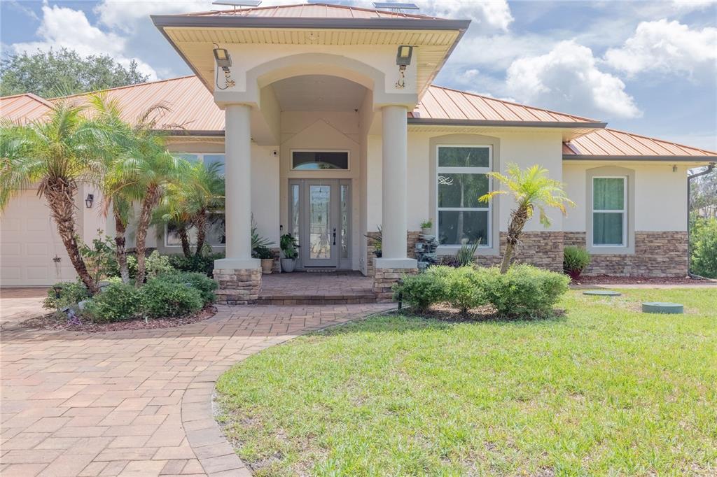 A single-story house with a metal roof, stone accents, and a paved walkway — 2815 2815 DAIRY RD, MELBOURNE, FL