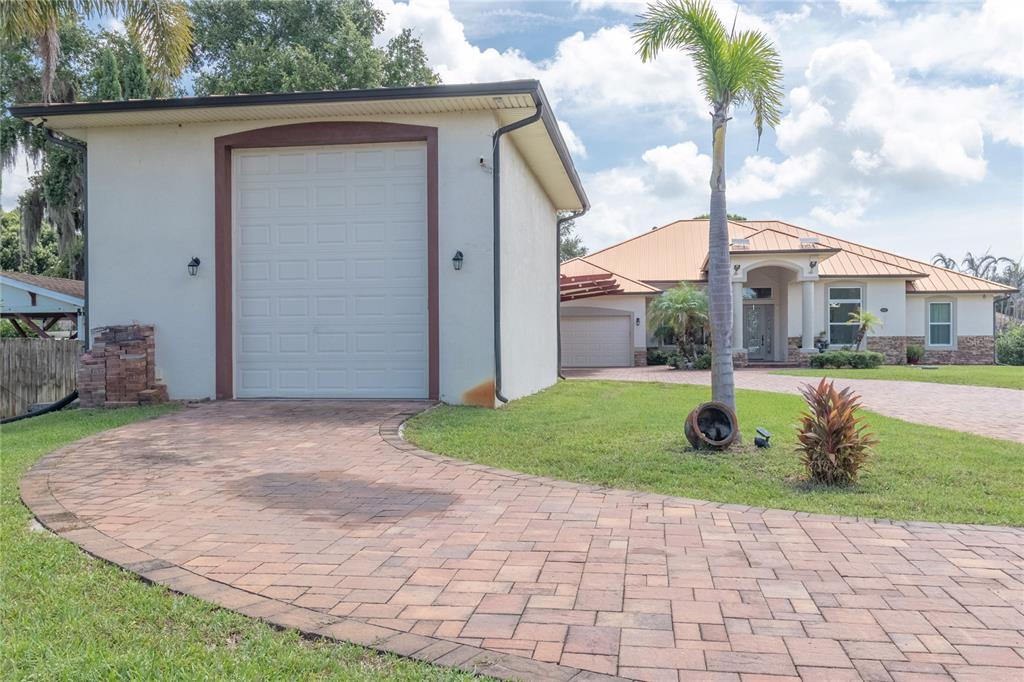 A detached garage stands in front of a house with a paved driveway and palm tree — 2815 2815 DAIRY RD, MELBOURNE, FL