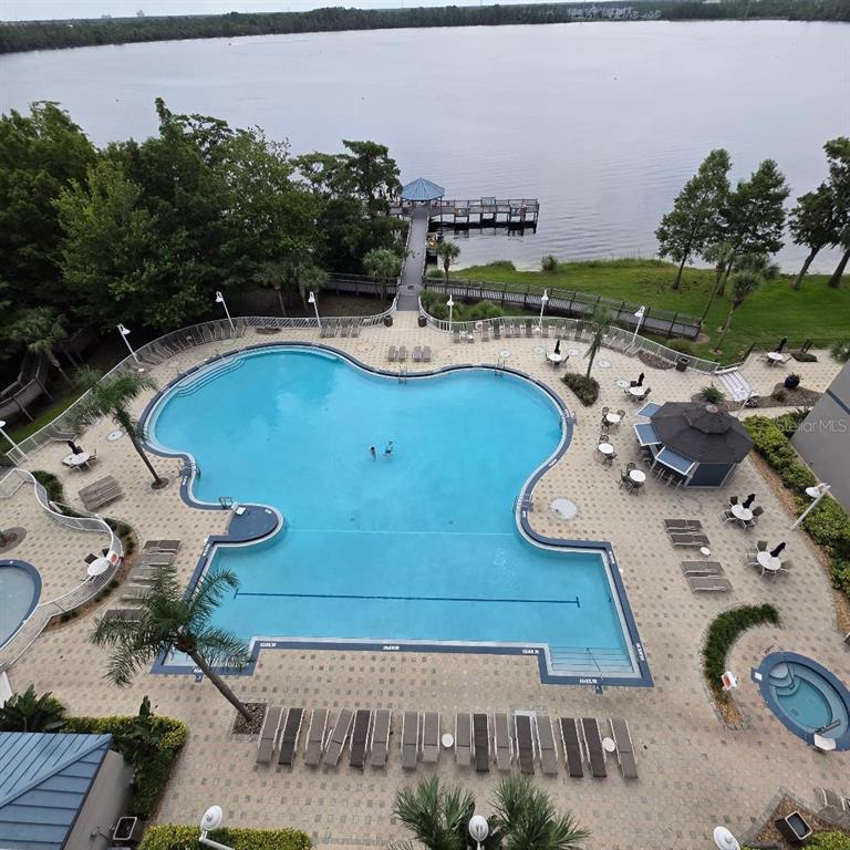 An aerial view shows a large swimming pool, a hot tub, and a pier on a lake — 13415 BLUE HERON BEACH DRIVE UNIT 609, ORLANDO, FL