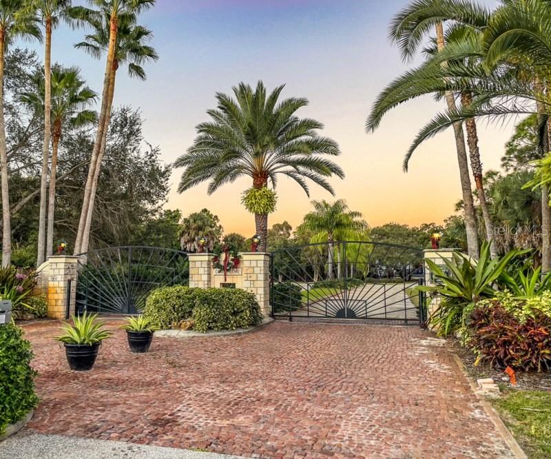 A brick driveway leads to a gated entrance flanked by stone pillars and palm trees — 10081 CREEKSIDE DRIVE, PLACIDA, FL