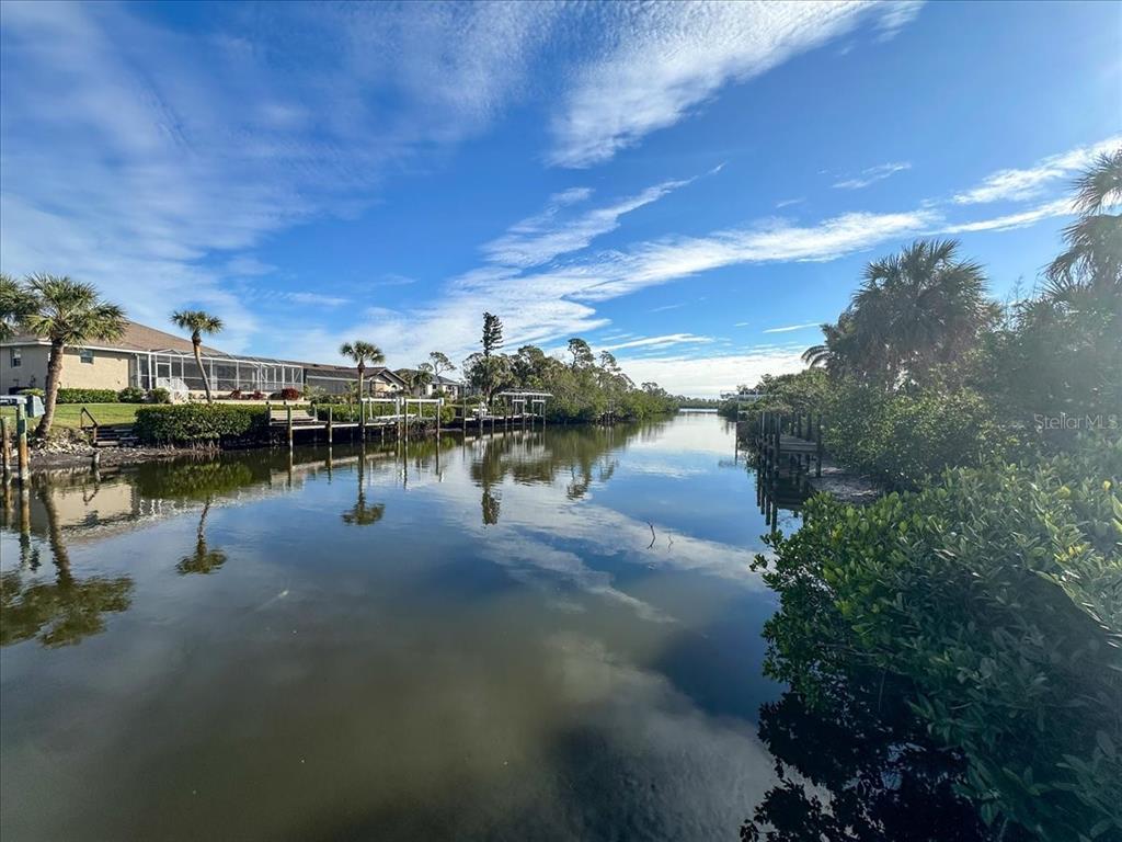 A canal view shows residential docks, palm trees, and mangroves under a blue sky — 10081 CREEKSIDE DRIVE, PLACIDA, FL