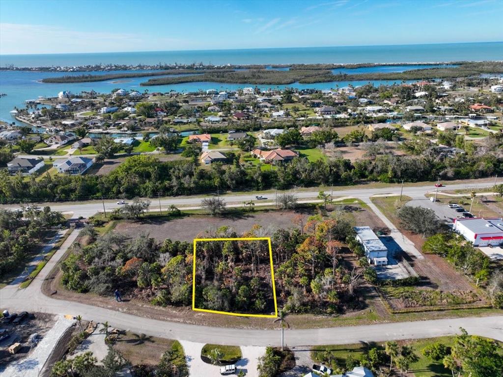 An aerial view shows a rectangular, wooded vacant lot outlined in yellow near a coastal road — 10081 CREEKSIDE DRIVE, PLACIDA, FL