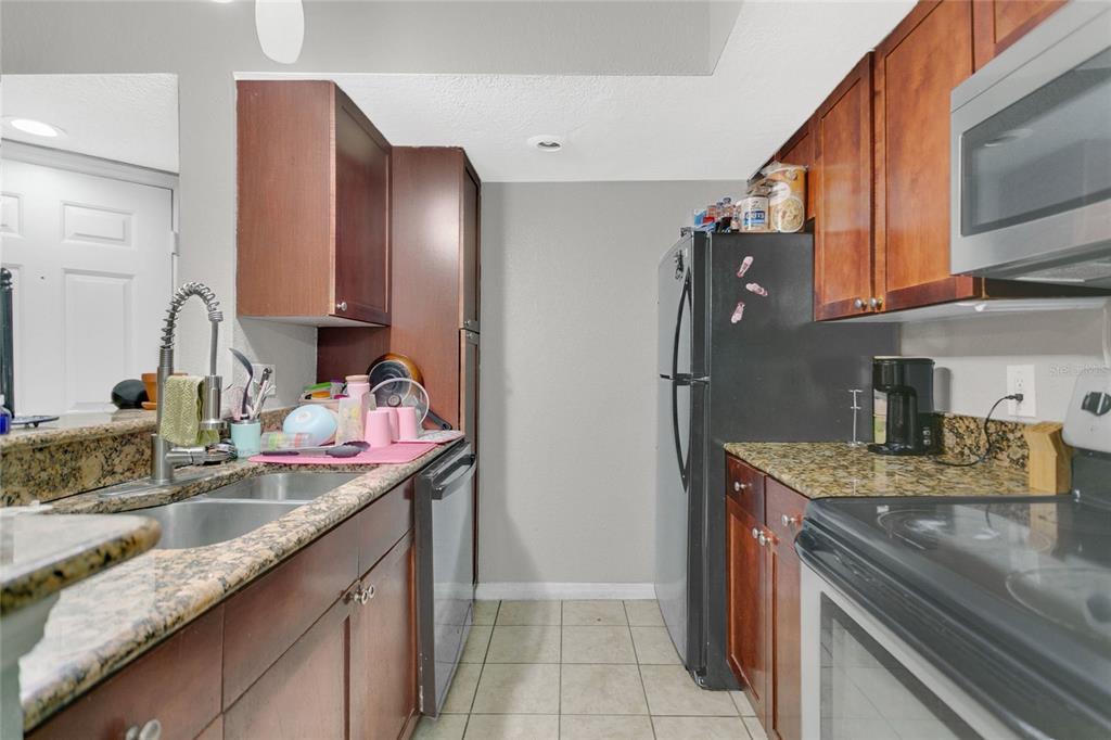 A room with tiled floors, white doors, a black chair, and dark curtains — 5148 CONROY ROAD UNIT 12, ORLANDO, FL