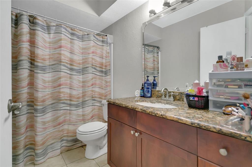 A living room with tile flooring, a black sofa, and an open kitchen with bar seating — 5148 CONROY ROAD UNIT 12, ORLANDO, FL