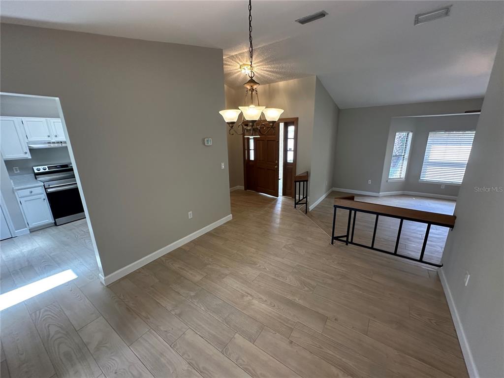 A dining area with wood-look tile flooring, a chandelier, and an adjacent kitchen — 840 MARAVAL COURT, LONGWOOD, FL