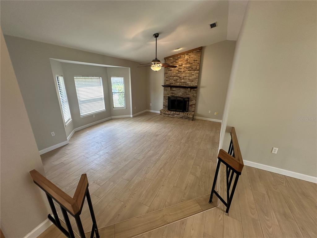 A living room features wood-look tile flooring, a brick fireplace, and a bay window — 840 MARAVAL COURT, LONGWOOD, FL