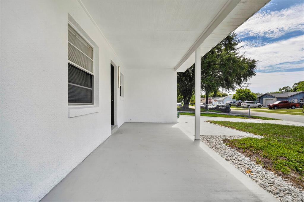 A covered concrete porch with a white exterior wall and a single support post — 2605 CHAR STREET, ORLANDO, FL