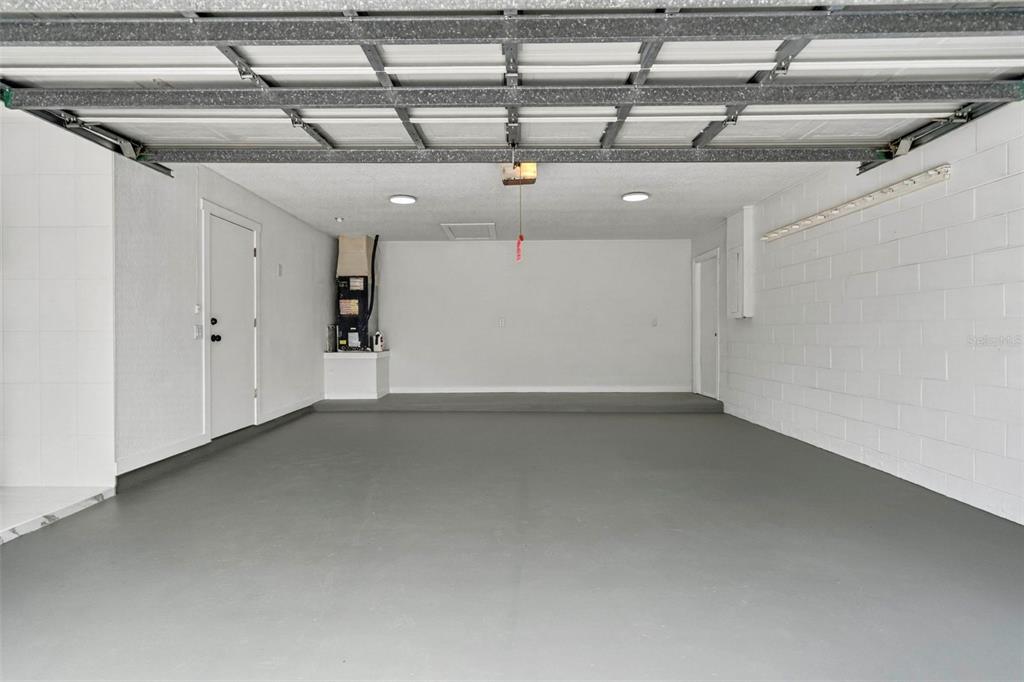 An empty two-car garage with gray epoxy floors, white walls, and a raised rear platform — 2605 CHAR STREET, ORLANDO, FL