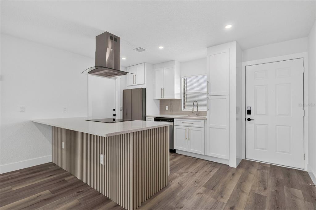 A modern kitchen features white cabinets, a slatted wood island, and dark wood-look flooring — 2605 CHAR STREET, ORLANDO, FL