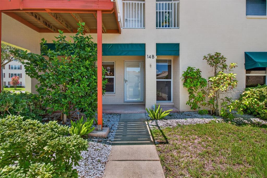 The exterior of a multi-story residential building features a concrete walkway leading to the front door — 6330 99TH WAY N UNIT 14B, ST PETERSBURG, FL