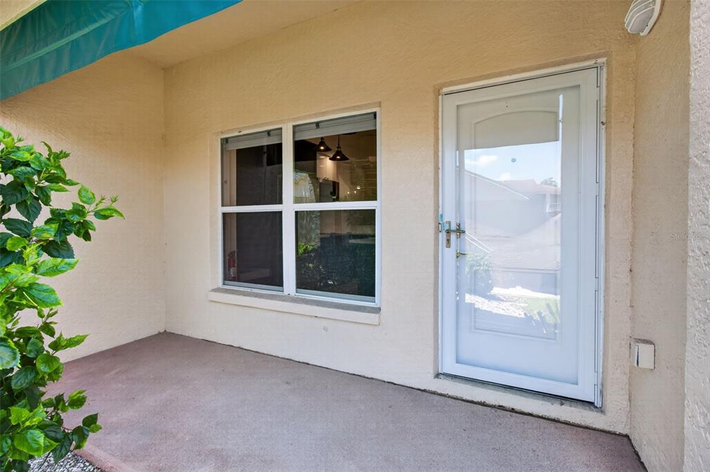 A beige exterior wall features a white storm door and a window overlooking a patio — 6330 99TH WAY N UNIT 14B, ST PETERSBURG, FL