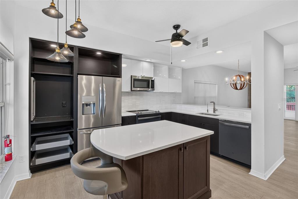 A kitchen features a white island, dark lower cabinets, white upper cabinets, and stainless appliances — 6330 99TH WAY N UNIT 14B, ST PETERSBURG, FL