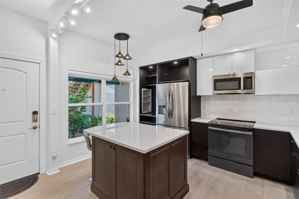 A modern kitchen features a dark wood island, stainless steel appliances, and white upper cabinets — 6330 99TH WAY N UNIT 14B, ST PETERSBURG, FL