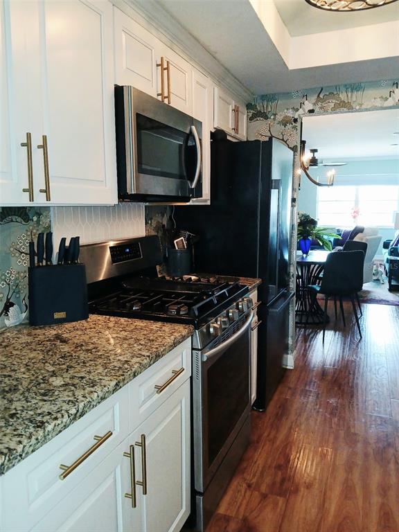 A kitchen features white cabinets, granite countertops, stainless steel appliances, and patterned wallpaper — 1900 59TH AVENUE N UNIT 312, ST PETERSBURG, FL