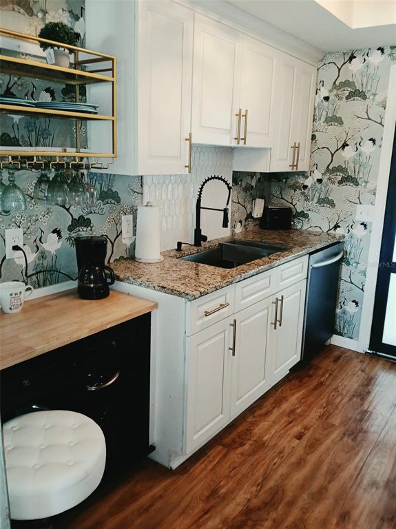 A kitchen features white cabinets, granite countertops, a black faucet, and crane-patterned wallpaper — 1900 59TH AVENUE N UNIT 312, ST PETERSBURG, FL