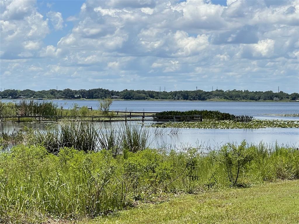 A wooden boardwalk extends into a lake surrounded by marshy vegetation under a cloudy sky — A T RACE ROAD, DUNDEE, FL