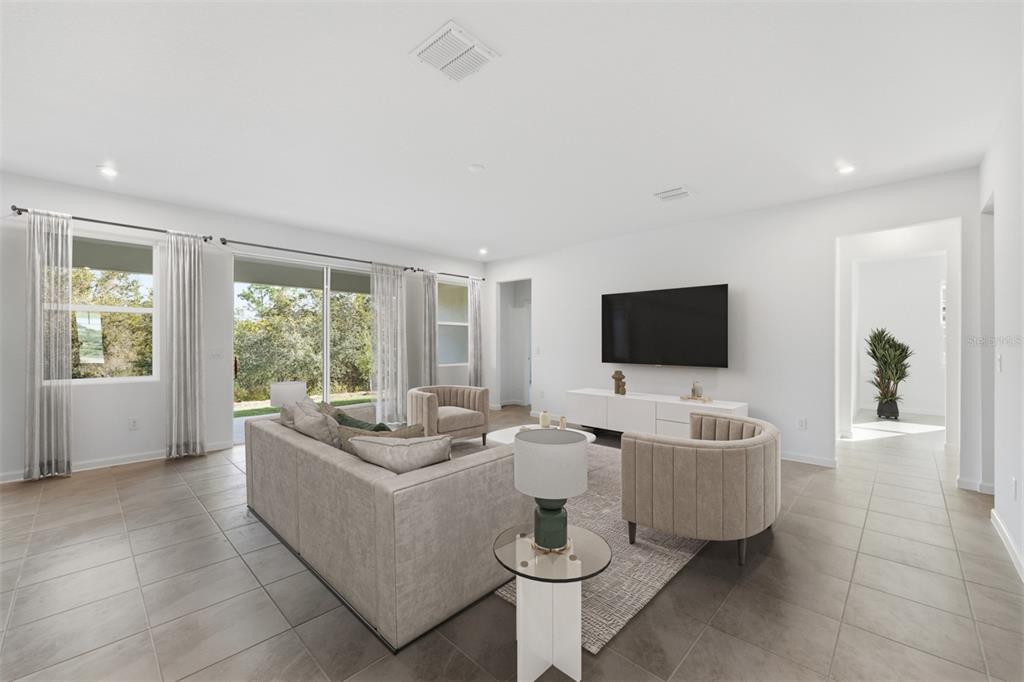 A living room features light tile floors, a neutral sofa, two armchairs, and a television — 324 FREE RANGE DRIVE, GROVELAND, FL