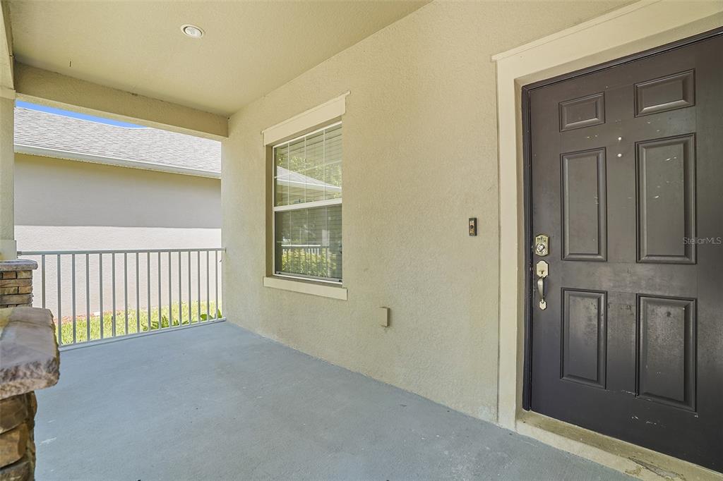 A covered porch features a dark front door, a single window, and a metal railing — 3205 BAYFLOWER AVE, ST CLOUD, FL