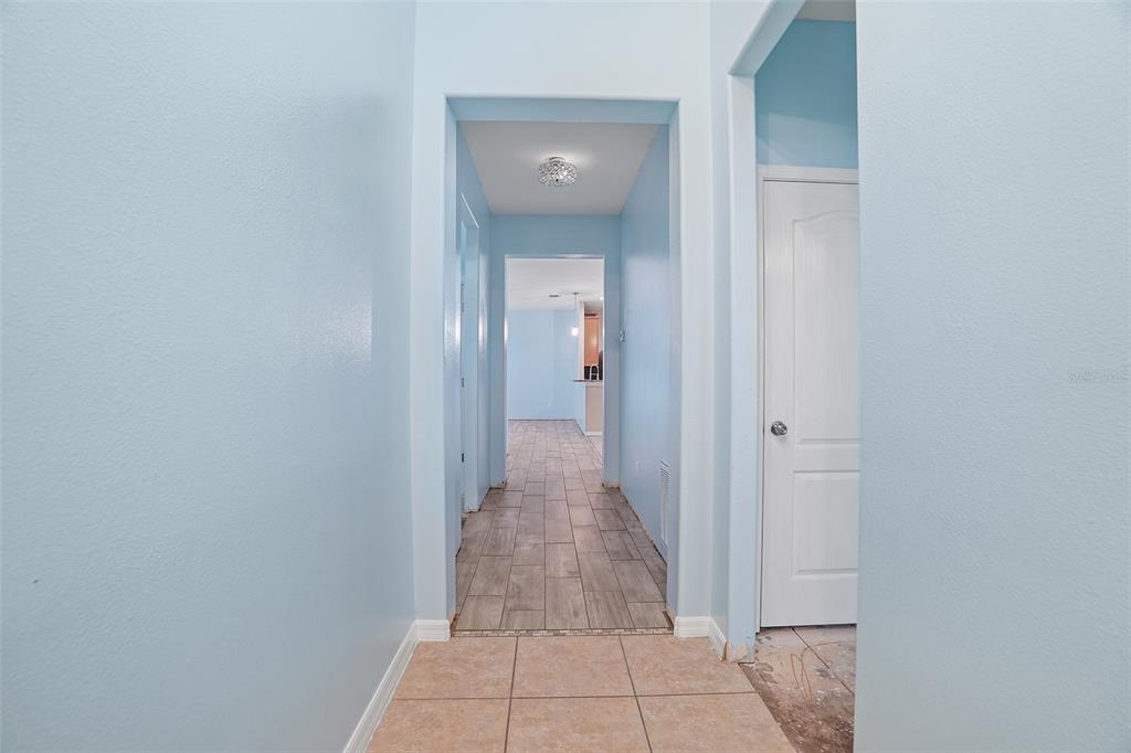 A hallway with light blue walls, tile flooring, and a white interior door — 3205 BAYFLOWER AVE, ST CLOUD, FL