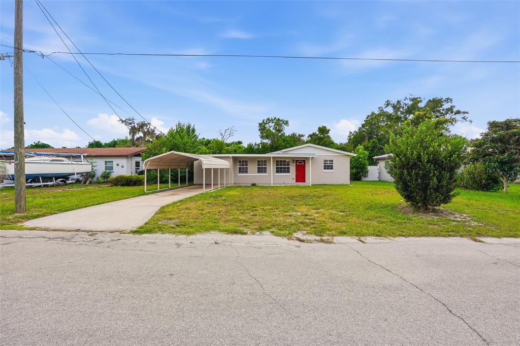 A single-story house with a beige exterior, a red front door, and a metal carport — 218 5TH JPV STREET, WINTER HAVEN, FL